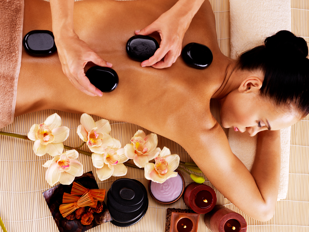 Adult woman having hot stone massage in spa salon. Beauty treatment concept.